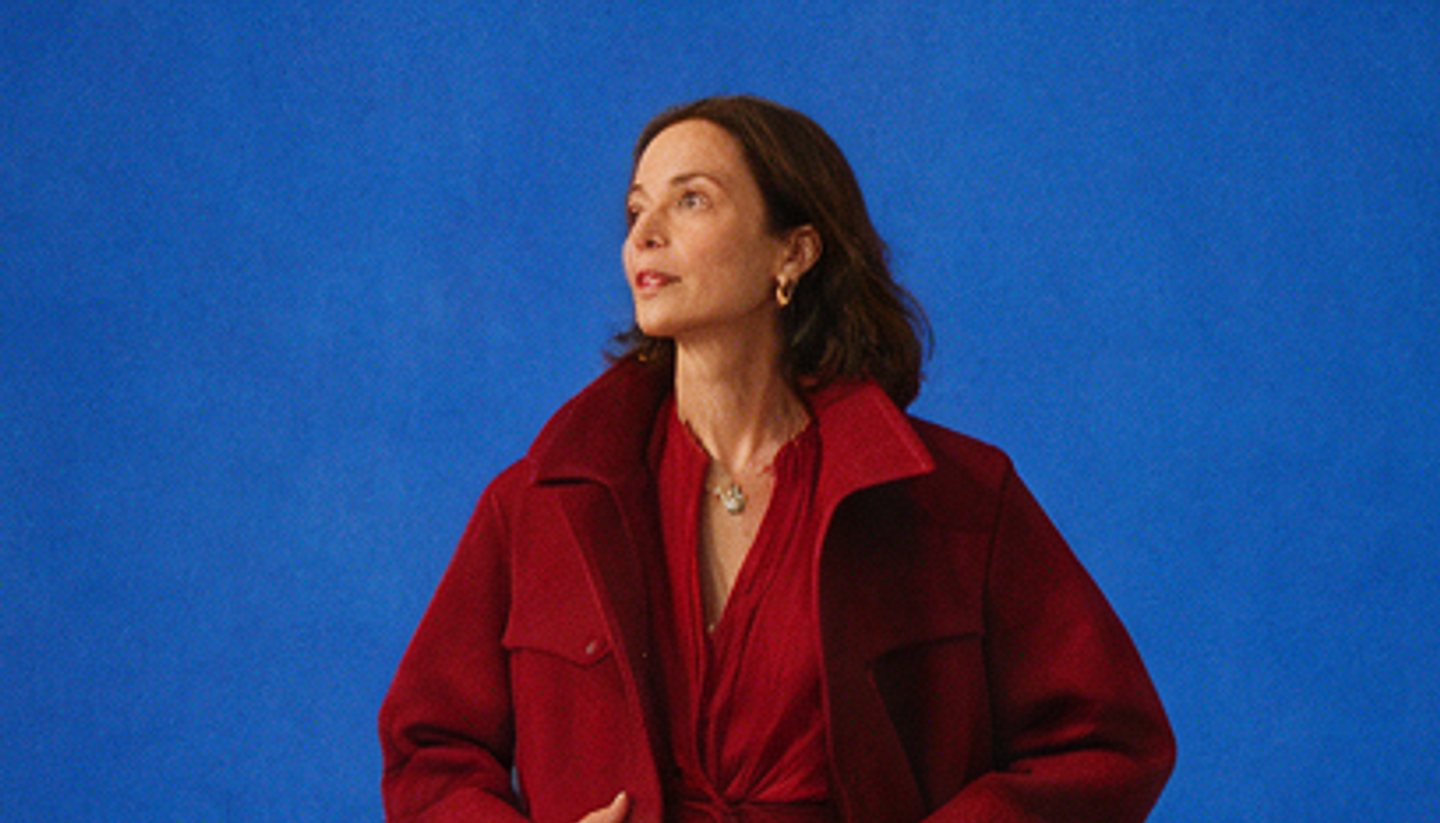 Portrait of an artist in a crimson coat against a deep blue studio backdrop