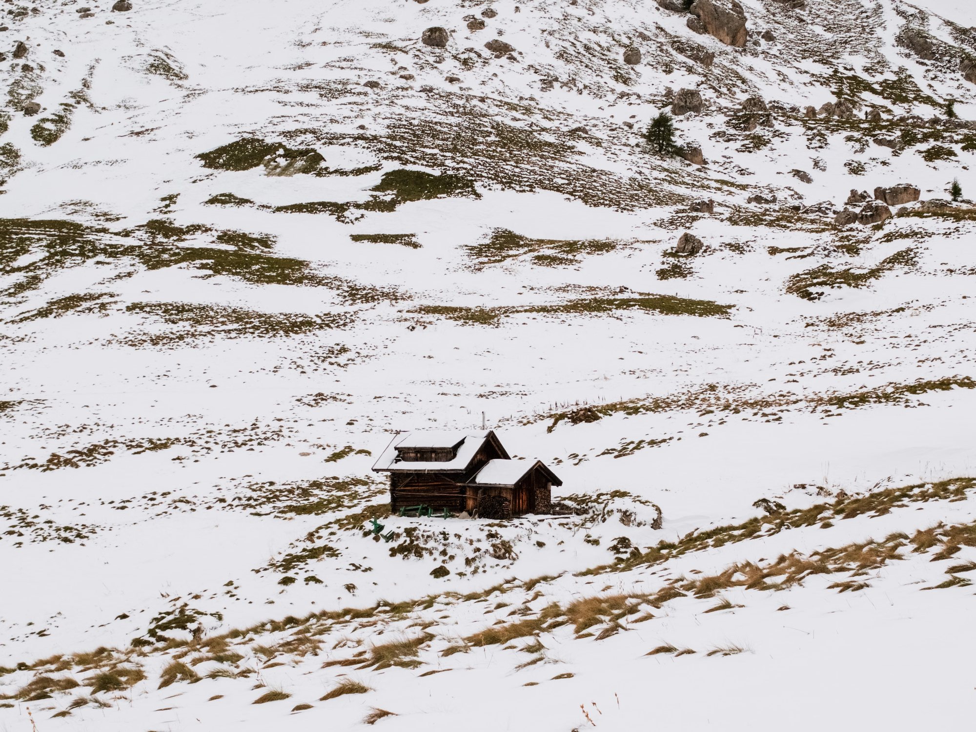 Small timber hut alone on a snow-covered mountainside in the Dolomites