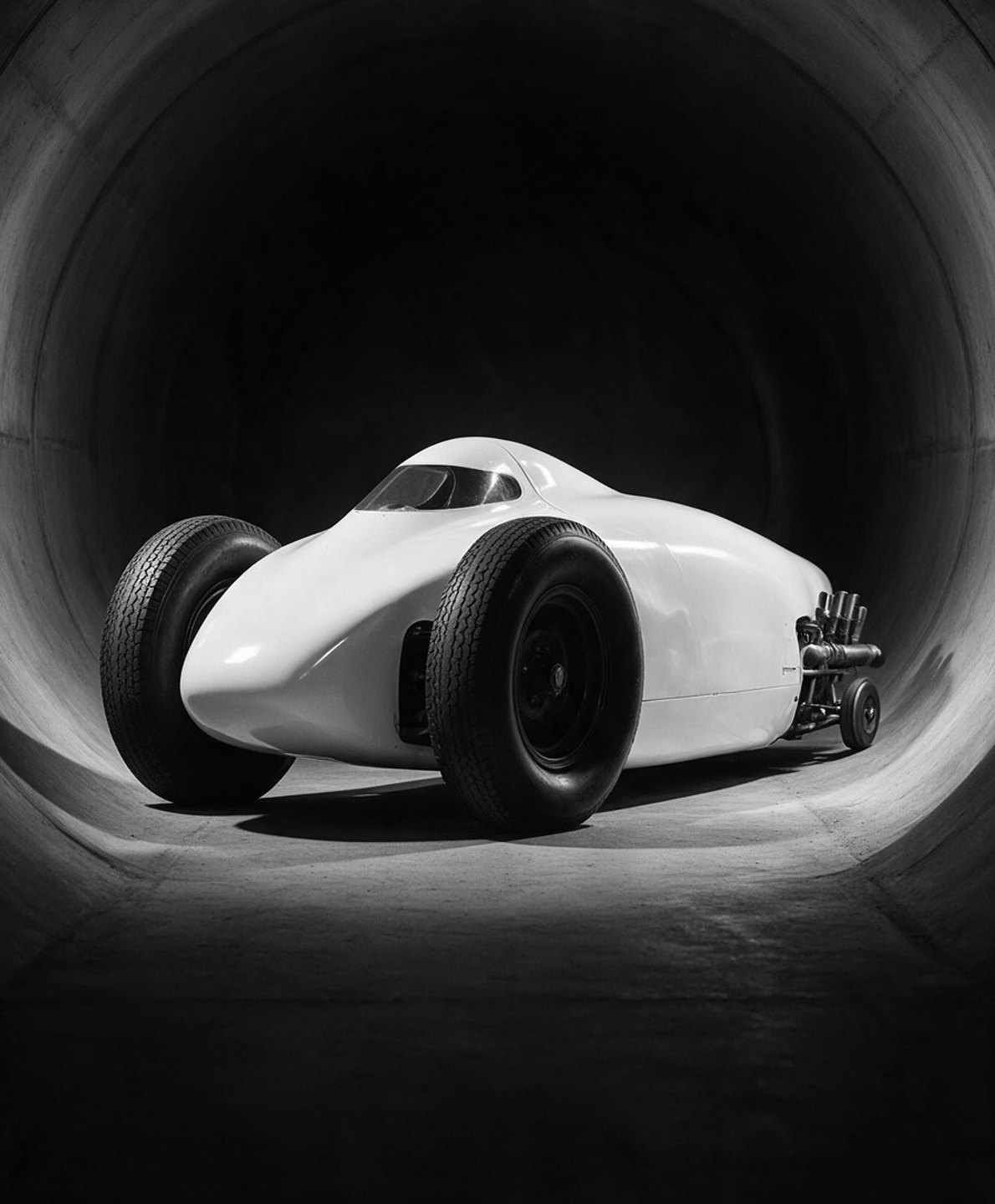Streamlined land-speed car with oversized tires inside a circular test tunnel