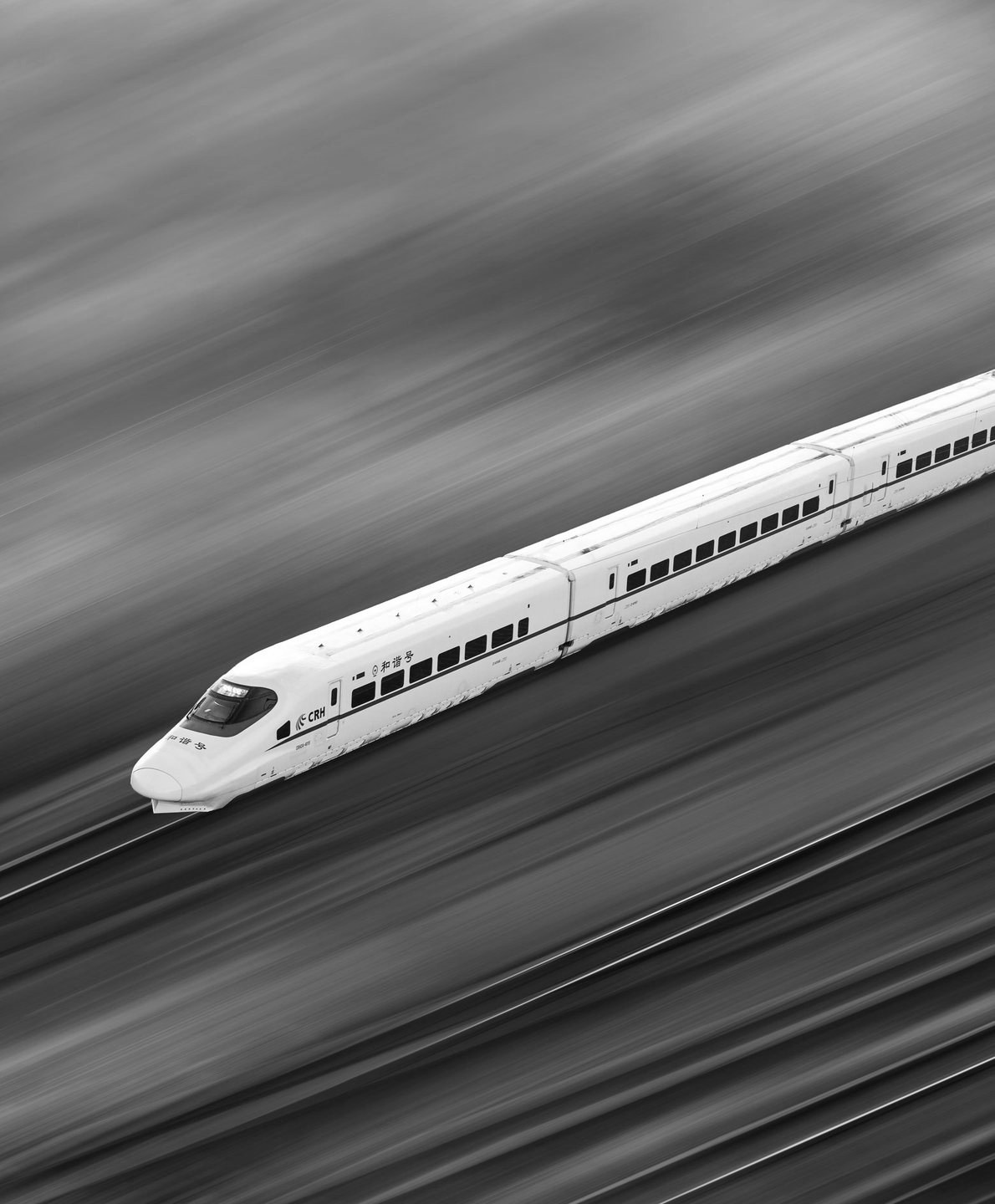 Nose of a white high-speed train in a dark hangar with receding lights