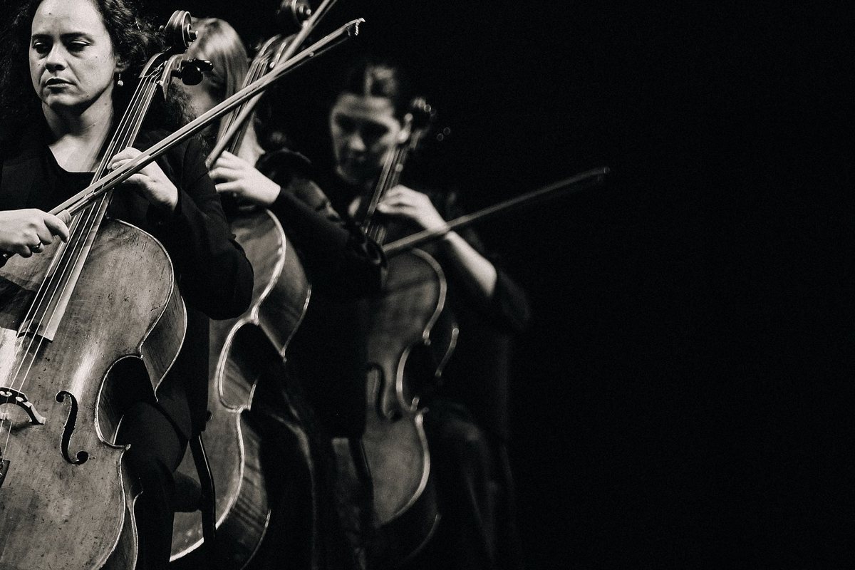 Cellists performing against a black stage