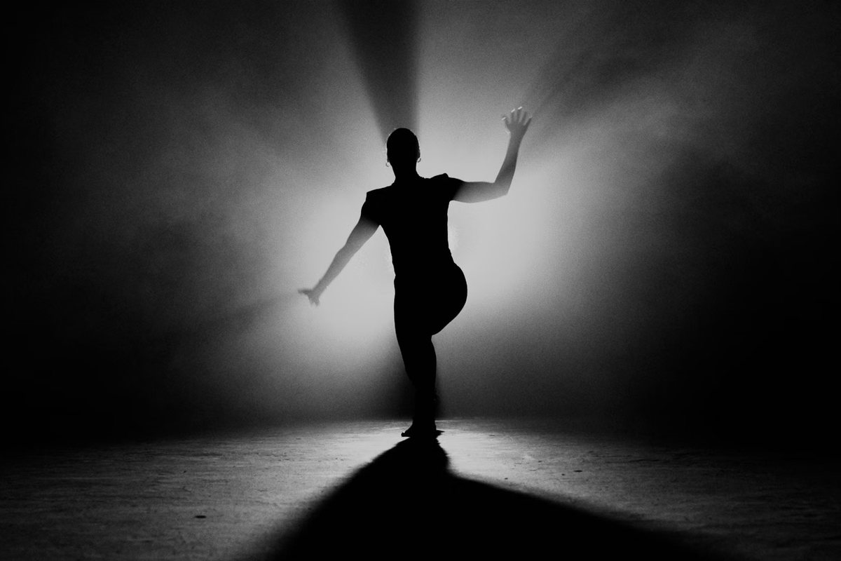 Dancer silhouetted in a cone of stage light