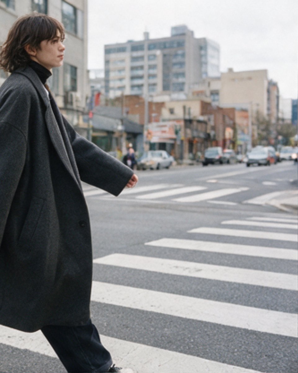 Figure in a long coat crossing a city street