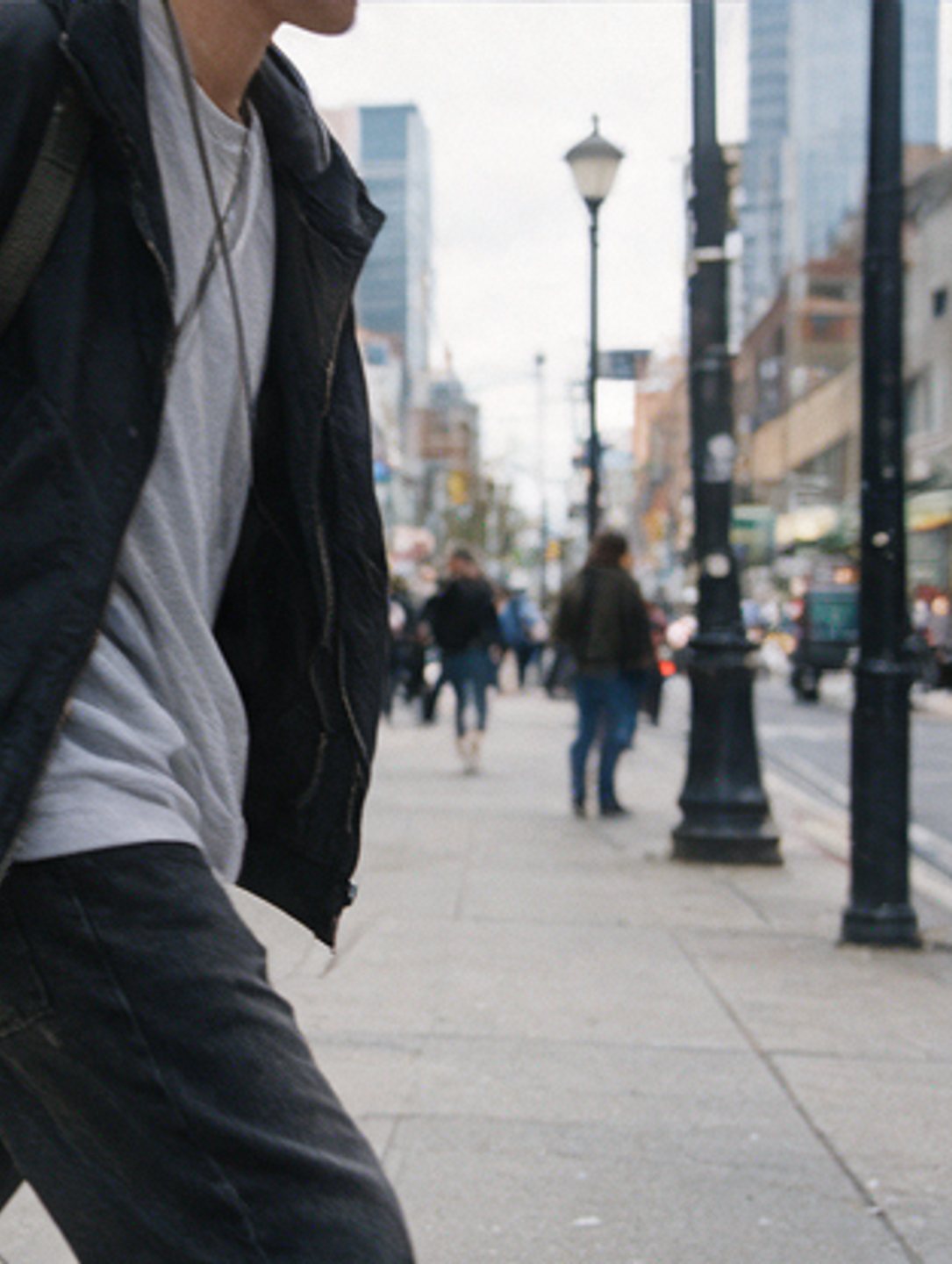 Pedestrian walking away down a busy avenue