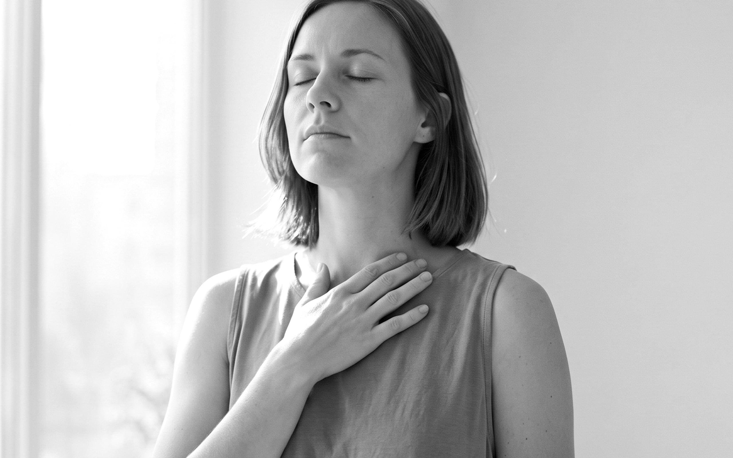 A woman at dusk with one hand on the opposite shoulder
