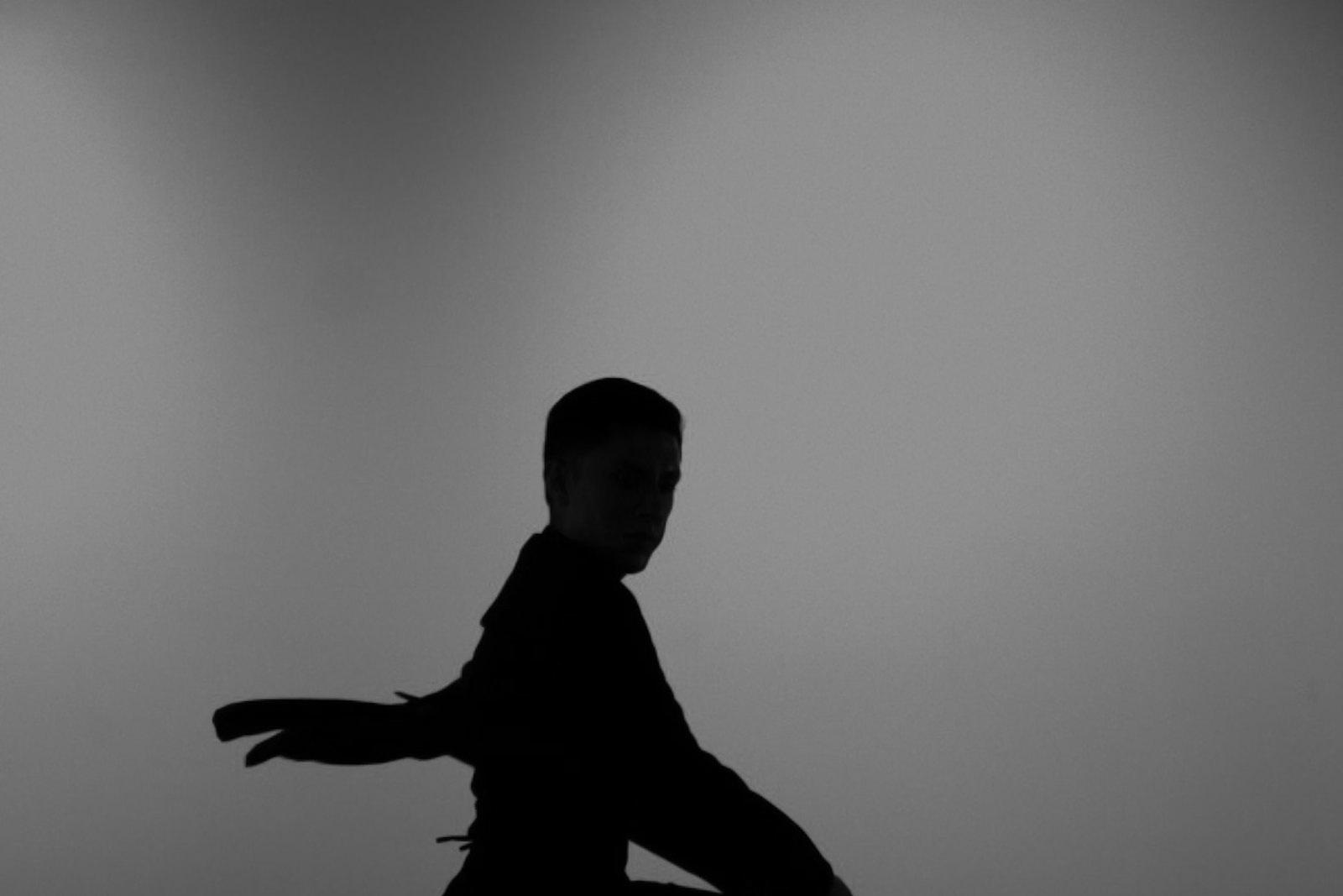 Dancer holding a low turning pose against a pale studio wall