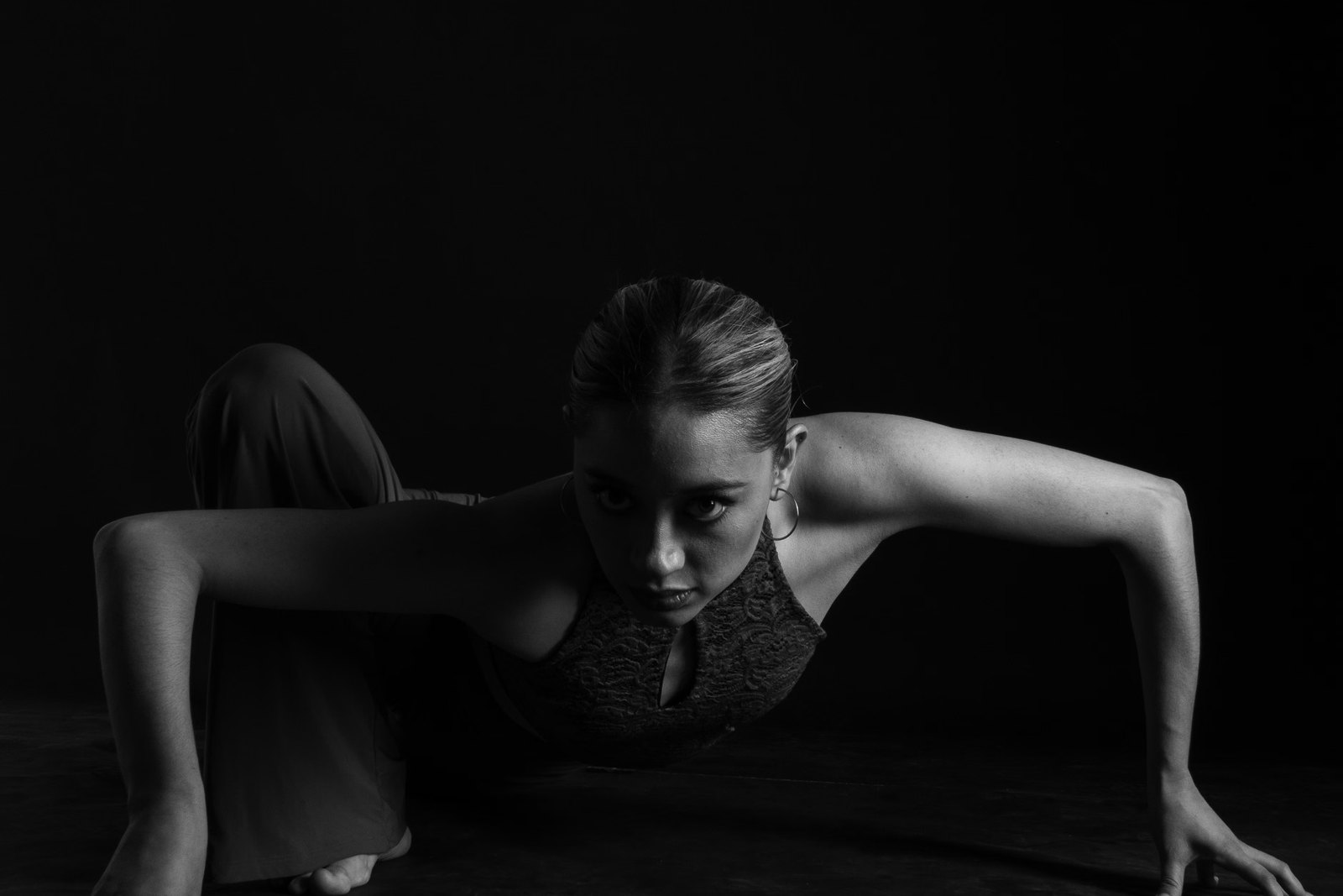 Dancer braced low to the floor in a darkened studio