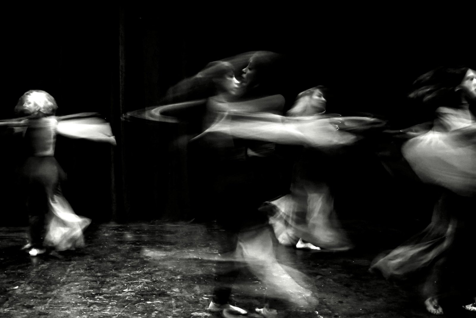 Ensemble of dancers blurred in motion across a stage