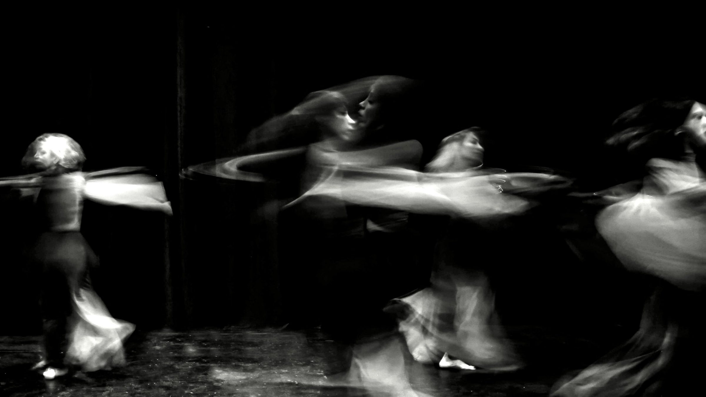 Dancers blurred in long exposure on a dark stage