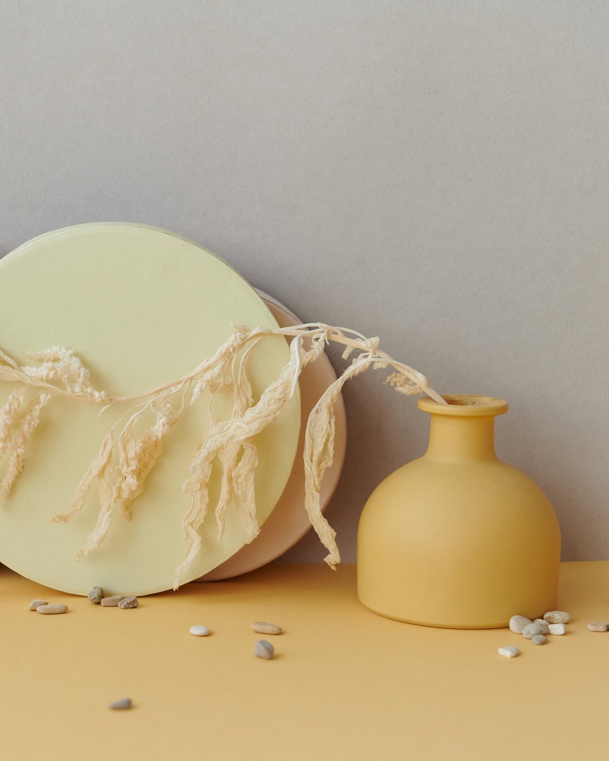 Cream disc and mustard vase with dried stems