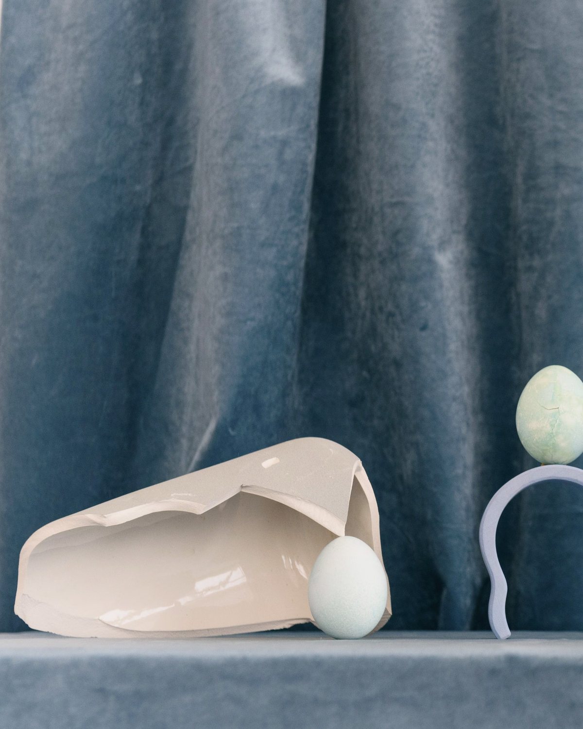 Broken ceramic and pale eggs on blue velvet