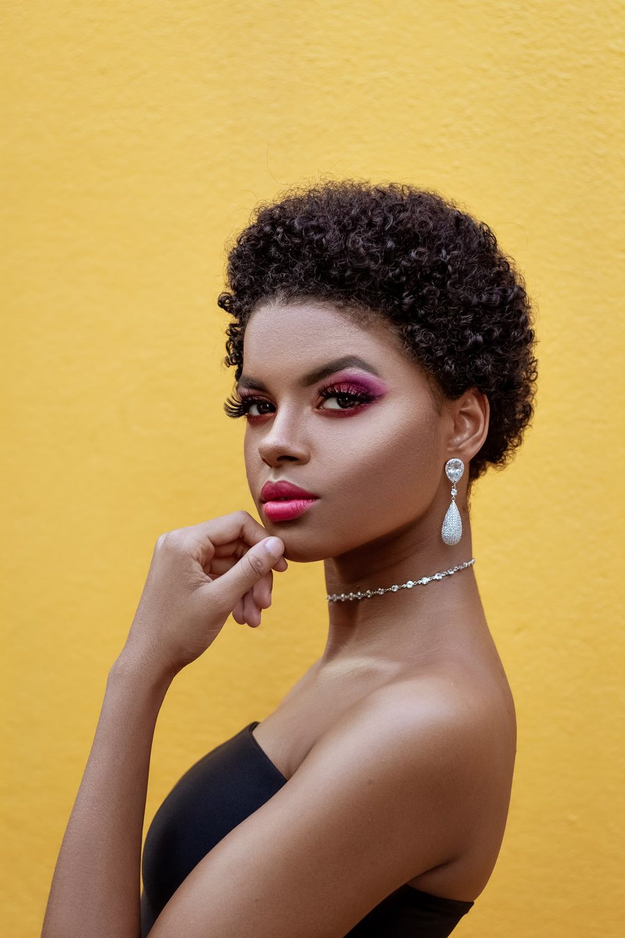 Portrait of a woman with jewelled earrings against a saffron yellow wall
