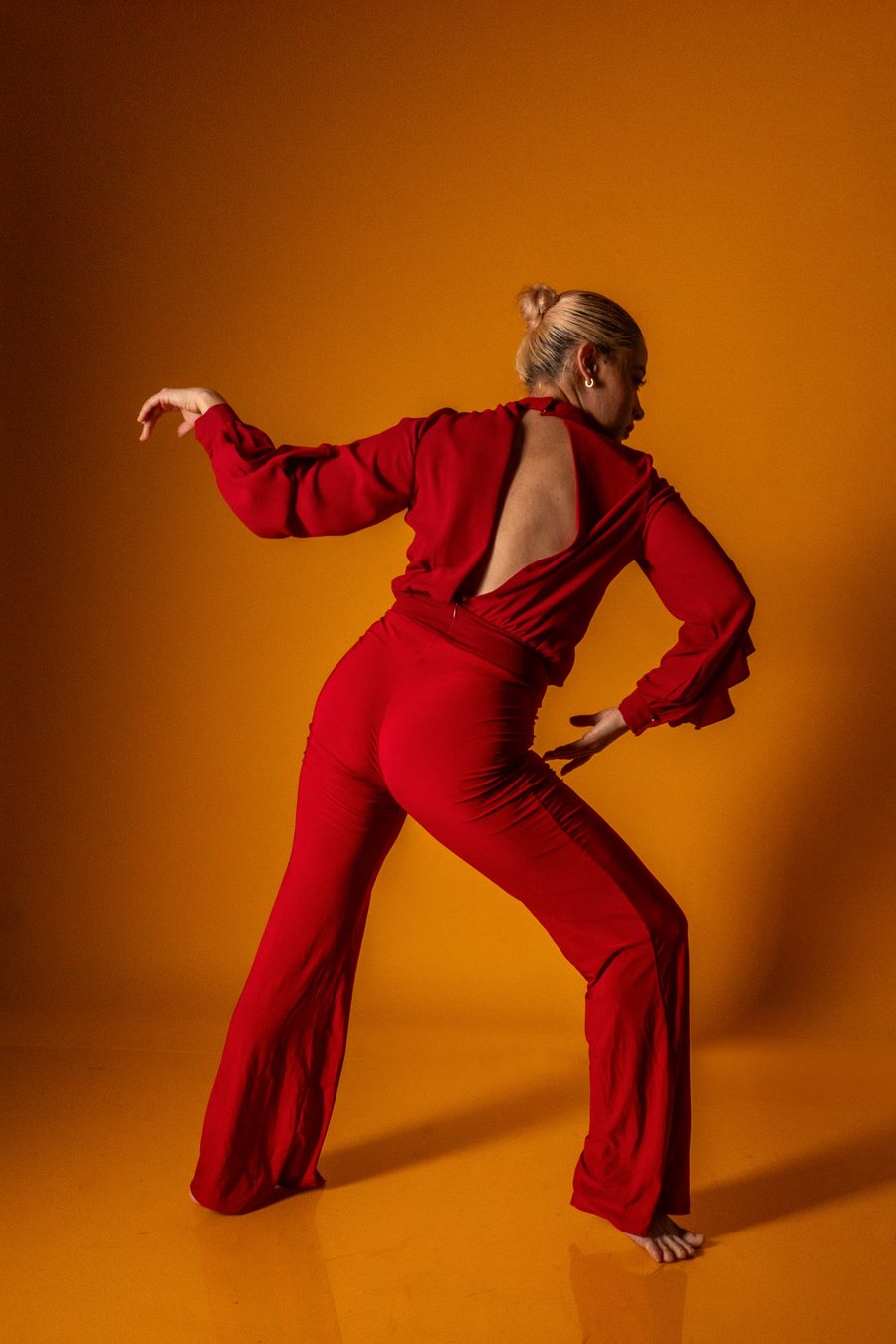 Dancer in red mid-turn against an amber studio backdrop