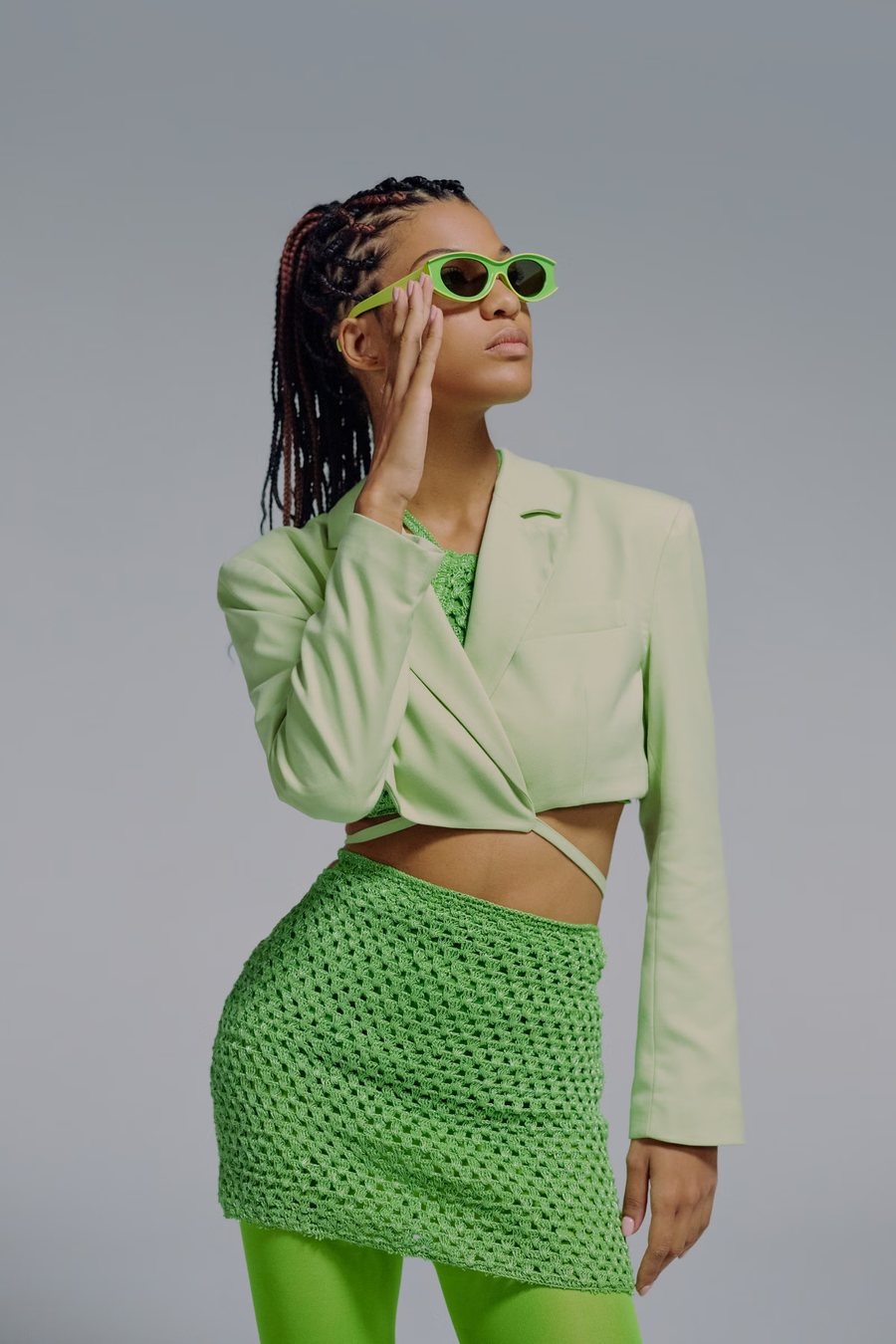 Model in a pale green cropped blazer and crochet skirt with green sunglasses