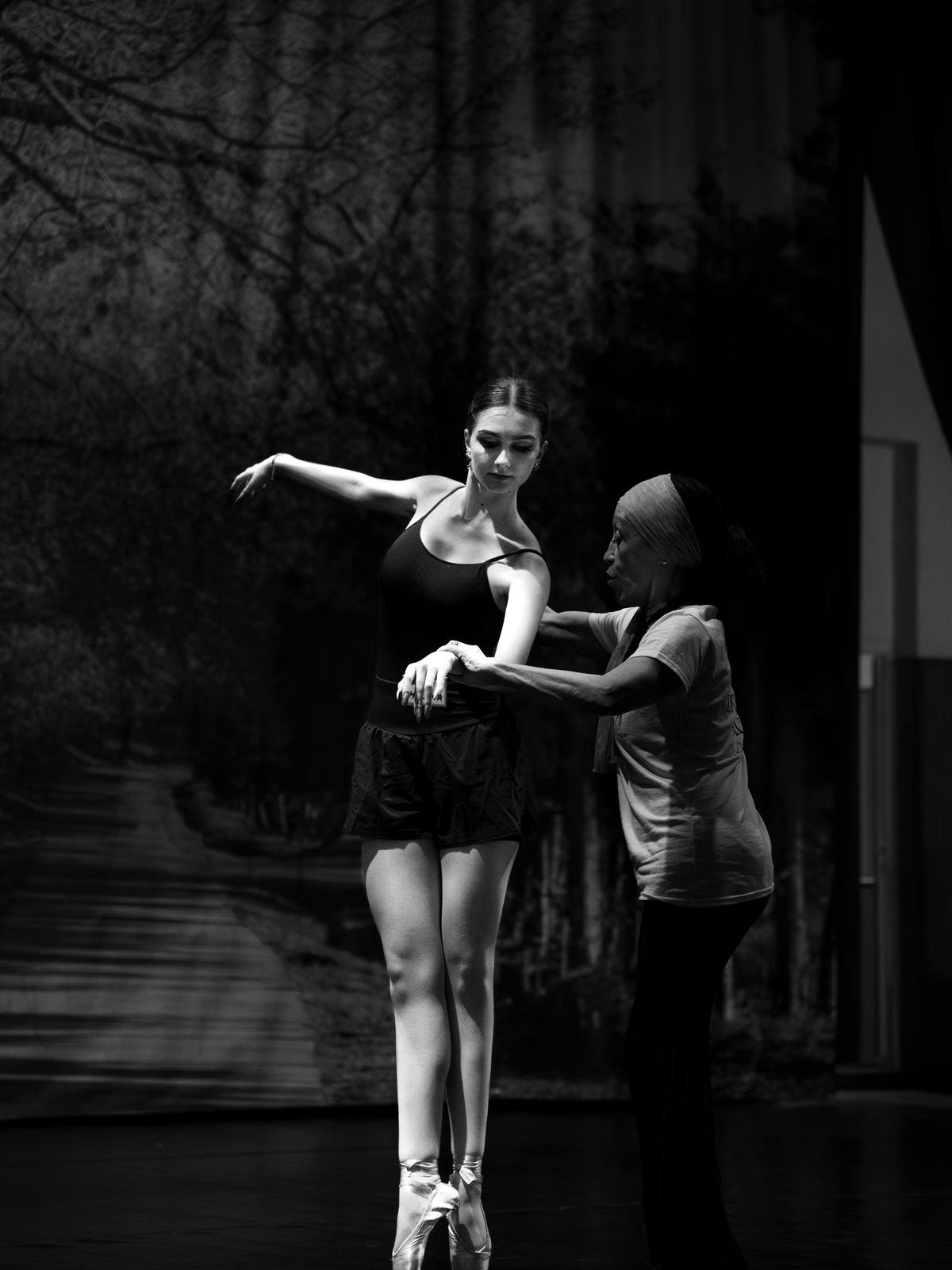Two dancers correcting a pose in rehearsal