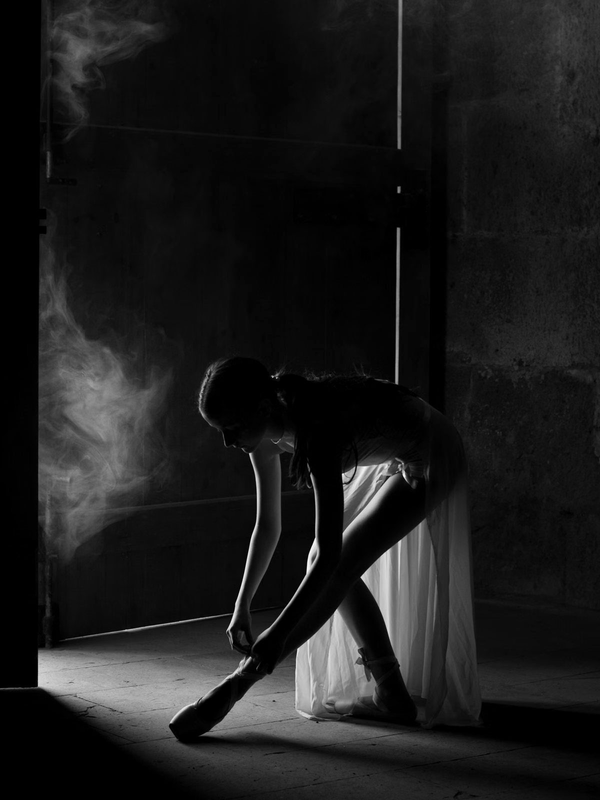 Dancer tying a shoe in stage haze