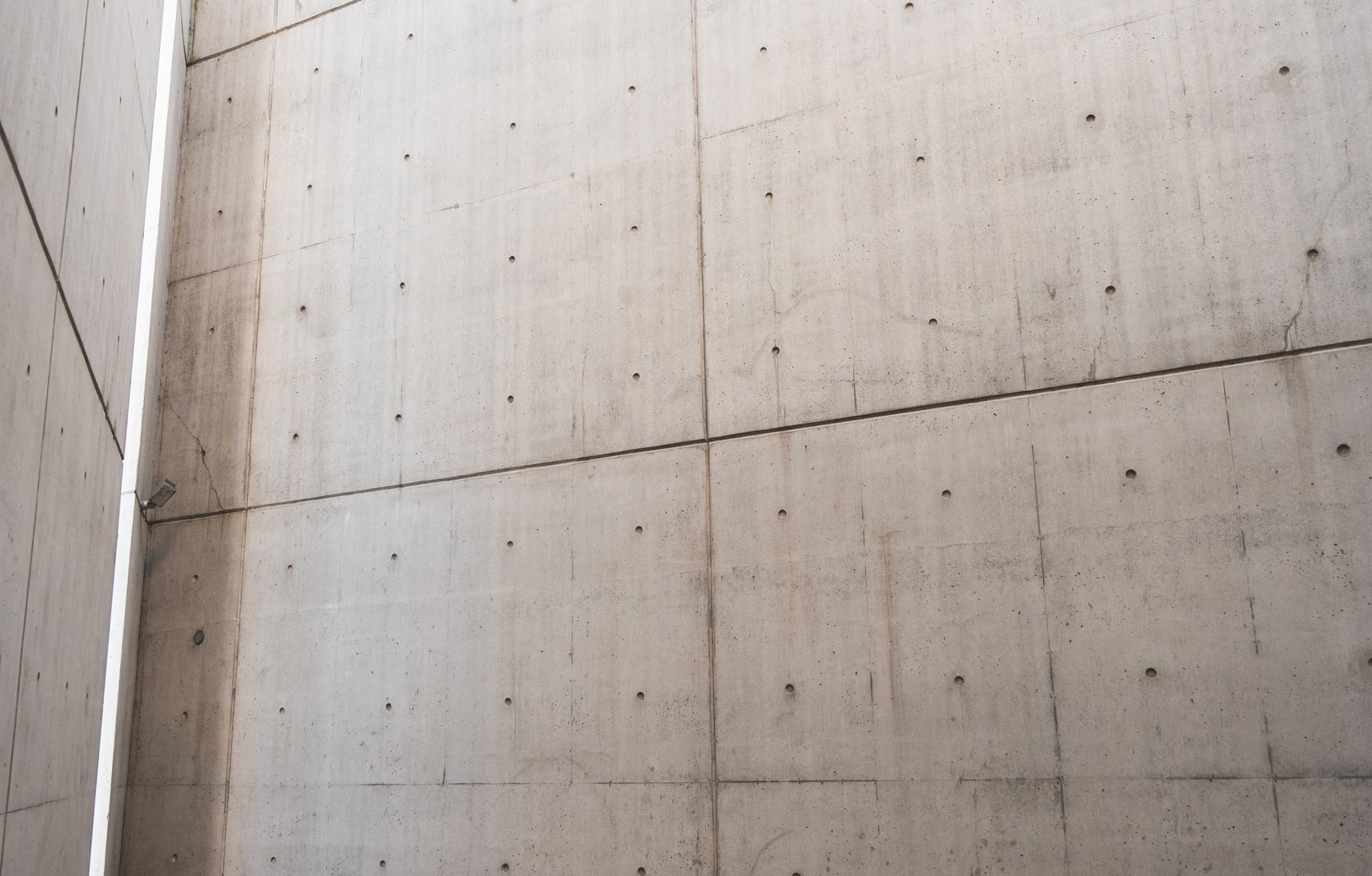 Board-marked concrete court, raw walls meeting at a slot of sky