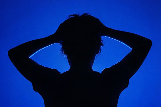 Figure in blue light, hands raised