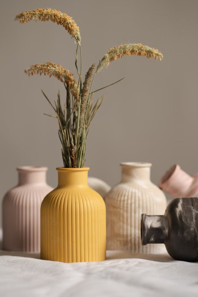 Ochre, pink and smoke glazed vases holding dried seed heads