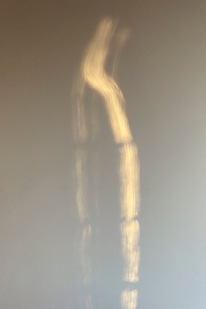 A single ribbon of sunlight falling down a pale wall