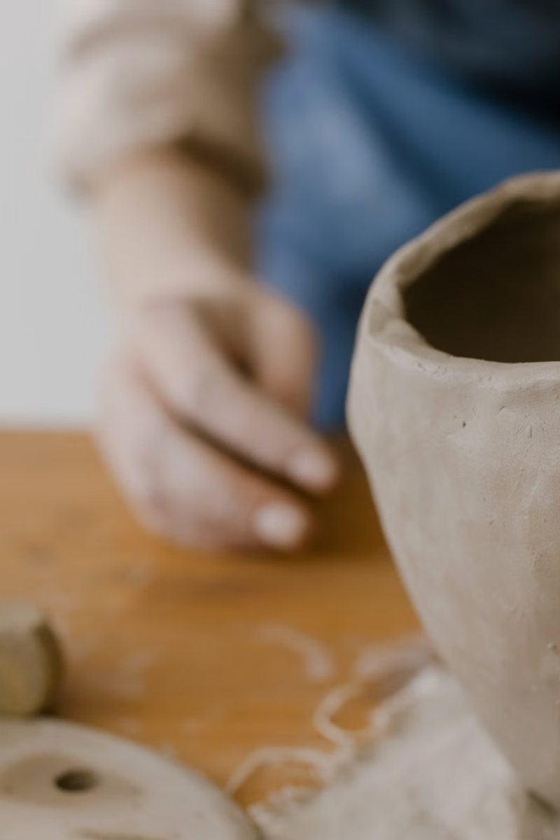 A hand smoothing the rim of an unfired bowl