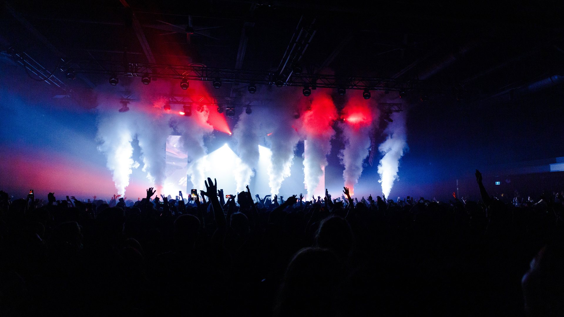 Crowd under red stage lights and smoke at a late-night set