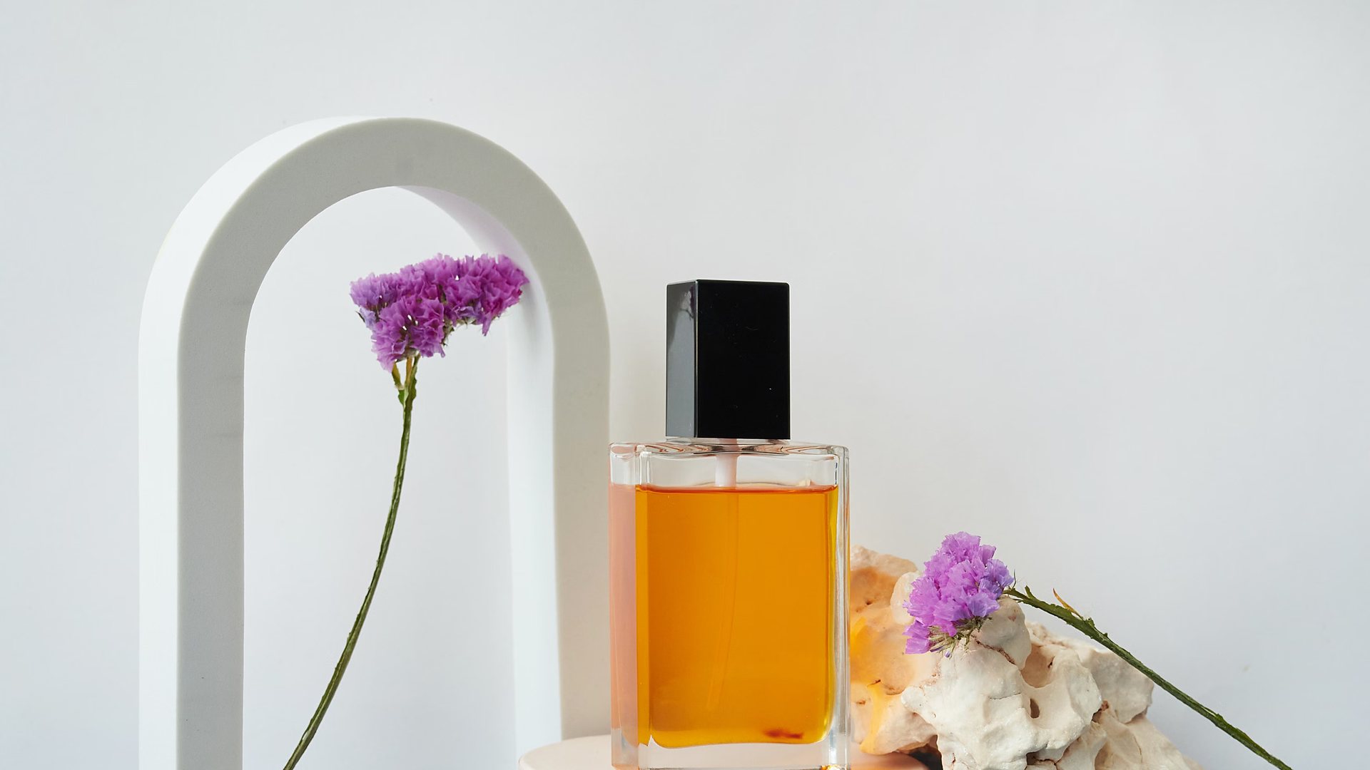 Amber perfume bottle beside a pale arch prop