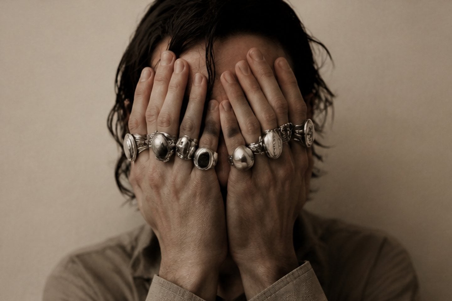 Hands wearing heirloom silver rings held over a face