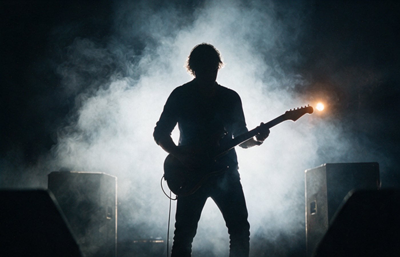 Guitarist silhouetted against stage smoke