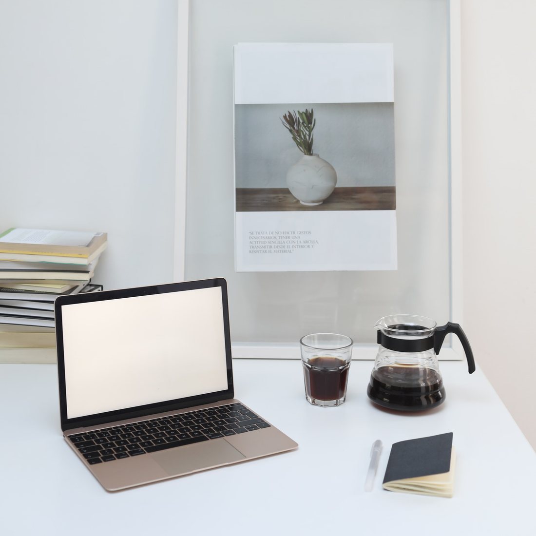 A tidy desk with a laptop, pour-over coffee, and a framed print