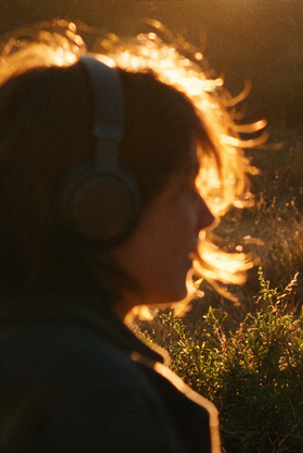 Profile of a person in headphones against the sun