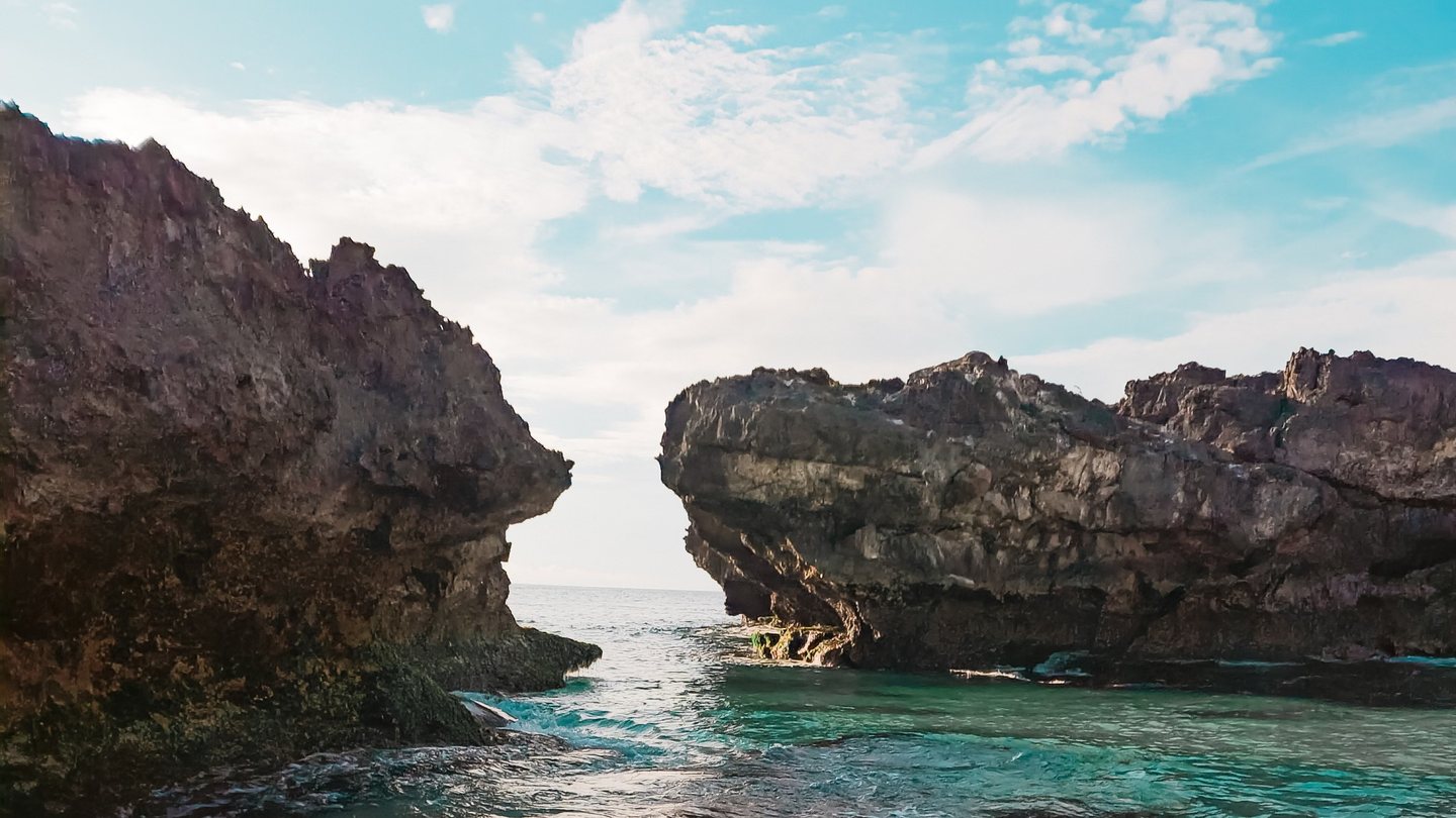 Turquoise cove framed by pale limestone rock under a bright midday sky