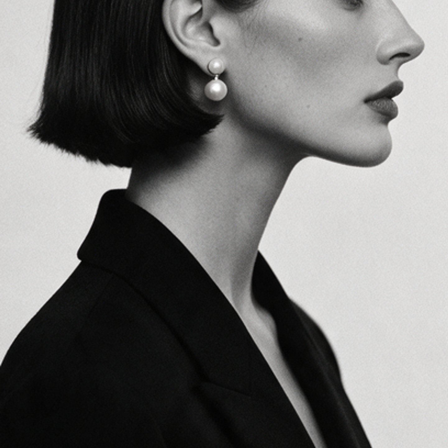Black-and-white profile of a woman with a sharp bob and pearl drop earring