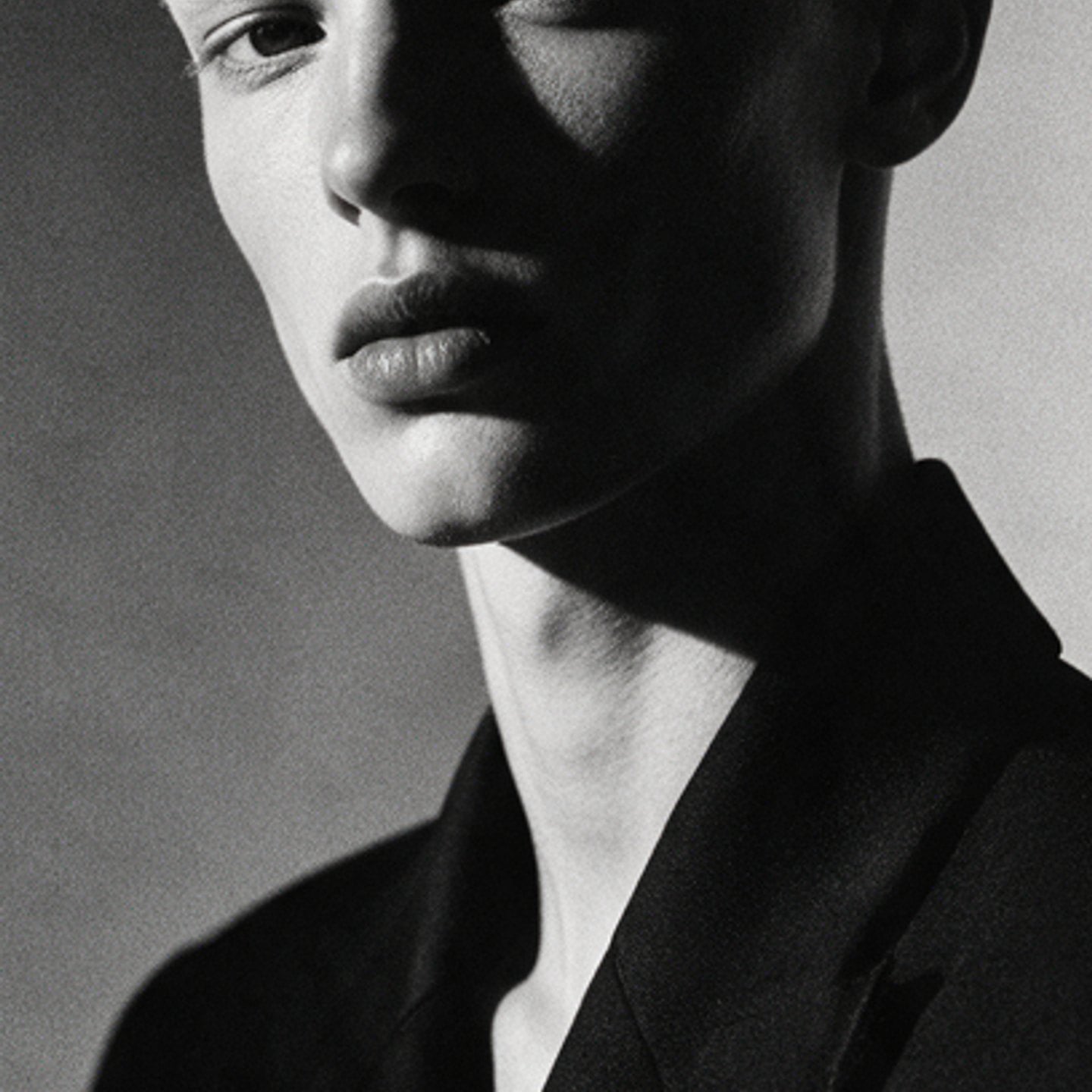Black-and-white portrait of a young man, half his face in hard shadow
