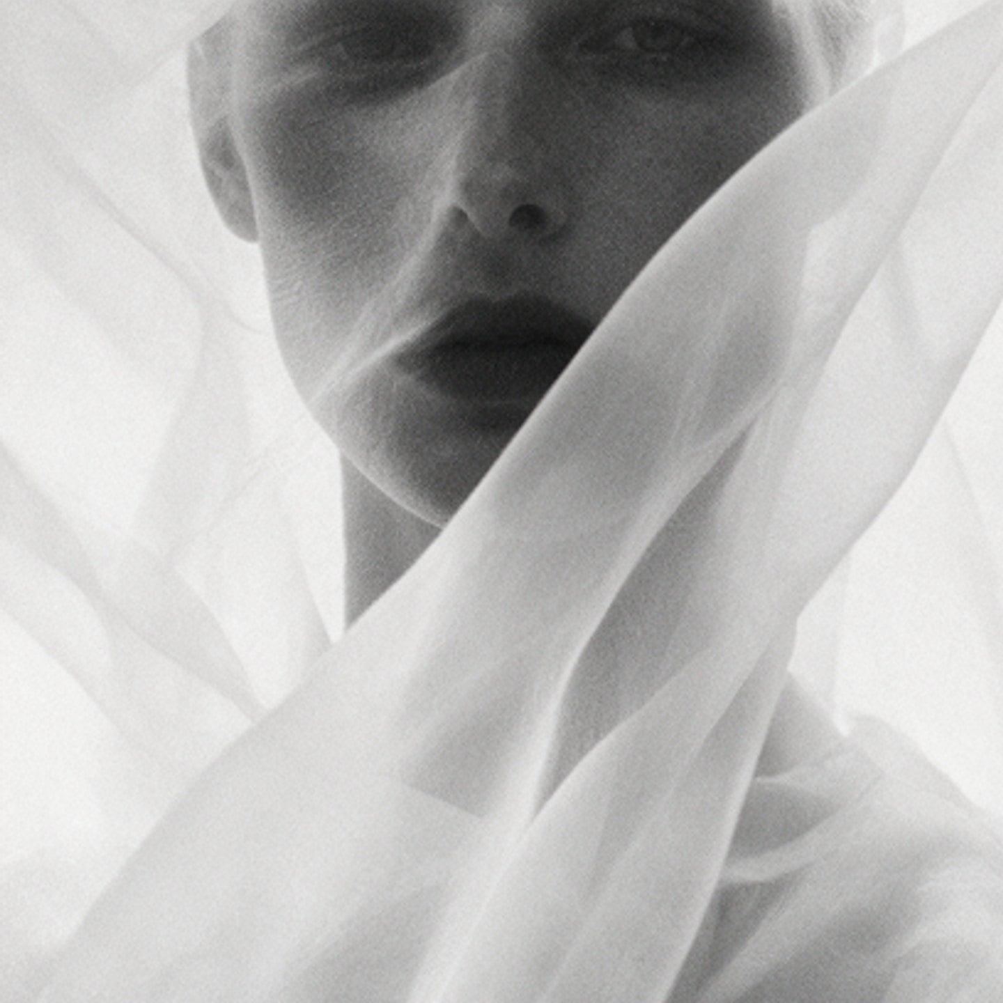 Portrait of a face softly veiled under folds of white organza