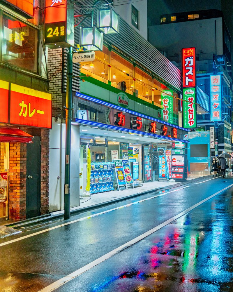 Rain-slicked street glowing with signage