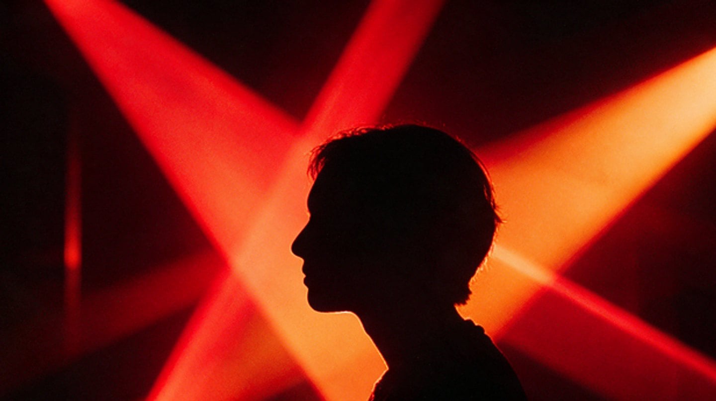 Musician in profile, lit only by red stage beams