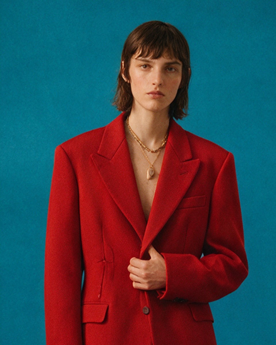 Evander Coren, executive producer, in a red blazer against a teal backdrop