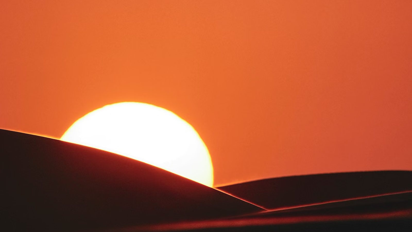 Sun cresting a dune at last light